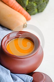 Pumpkin cream soup in a ceramic bowl on a white table. Copy space