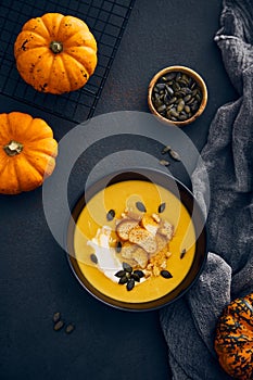 Pumpkin cream soup with croutons on dark background