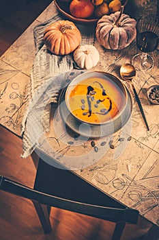 Pumpkin cream soup with pumpkin seeds on decorated kitchen table