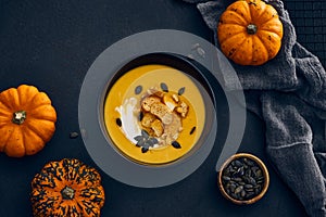 Pumpkin cream soup with seeds on dark background