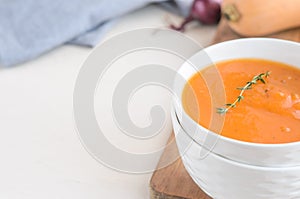 Pumpkin cream soup on a white table. Copy space