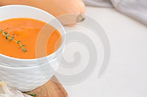 Pumpkin cream soup on a white table. Copy space