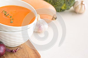 Pumpkin cream soup on a white table. Copy space