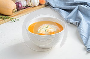 Pumpkin cream soup on a white table. Copy space