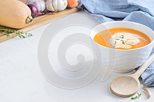 Pumpkin cream soup on a white table. Copy space