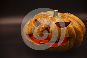 Pumpkin that is cut into a ghost face for Halloween, placed in a scary atmosphere, with candles shining in the dark. For use on Ha