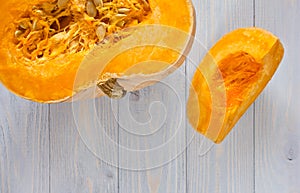 Pumpkin cut in half and piece on blue wooden background.