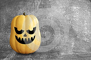 Pumpkin on a dark textured background with scary Halloween face. Autumn themed banner with space