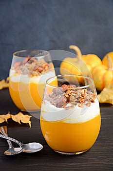 Pumpkin dessert with yogurt and homemade granola on dark wooden table