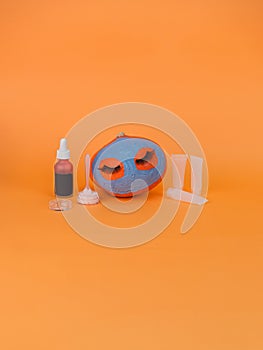 Pumpkin with facial mask on orange background