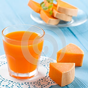 Pumpkin fresh juice in beautiful glasses and jug with pieces of ripe vegetable on white wooden background. Sweet orange juice. Hea