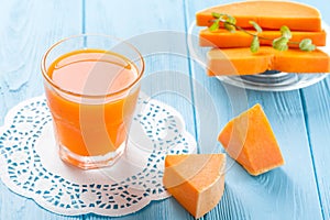 Pumpkin fresh juice in beautiful glasses and jug with pieces of ripe vegetable on white wooden background. Sweet orange juice. Hea