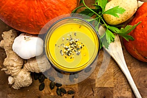 Pumpkin ginger soup, with parsley on dark wooden background.