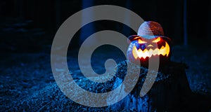 Pumpkin for Halloween with blue lighting the woods on stump with moss.