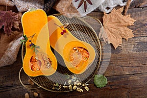 Pumpkin halves on metal gold tray on wooden table, autumn harvest concept, top view
