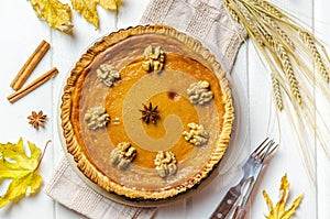 Pumpkin homemade vegan pie and spices cinnamon, anis, orange pumpkins with yelllow dry autumn leaves decor on dark table