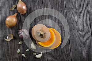 Pumpkin and ingredients for cooking over dark wooden background.