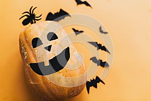 Pumpkin jack lantern and black bats, ghost, spider paper decorations on yellow background, copy space. Trick or treat concept.