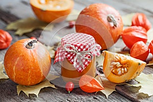 Pumpkin jam, puree or sauce and pumpkins on wooden table.