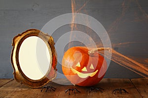 Pumpkin next to blank photo frame on wooden table