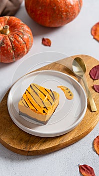 Pumpkin orange cheesecake with chocolate for Thanksgiving. Pumpkins and autumn leaves on the background. Autumn dessert. Healthy
