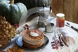 Pumpkin pancakes with cream and jam on a background of autumn still life