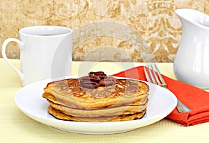 Pumpkin pancakes garnished with pecan halves.