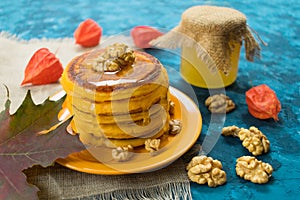 Pumpkin pancakes with honey and nuts on a blue background.
