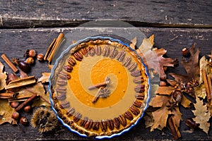 Pumpkin Pie with pecan nut and cinnamon on rustic background, top view, copy space. Homemade autumn pastry for Thanksgiving