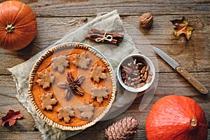 Pumpkin pie with pecan nuts on wooden background