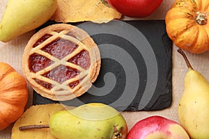 pumpkin pie and seasonal fruits and vegetables on wooden background