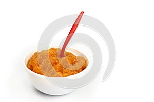 Pumpkin porridge in a bowl with a spoon isolated on white baby or vegan food