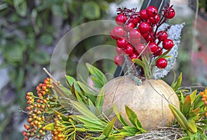 Pumpkin with red berries and green leaves on a straw.
