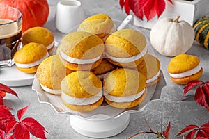 Pumpkin sandwich cookies with cream cheese on a gray concrete bsckground. Spicy autumn dessert. Copy space