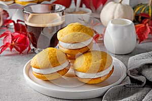 Pumpkin sandwich cookies with cream cheese on a gray concrete bsckground. Spicy autumn dessert. Copy space