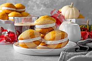 Pumpkin sandwich cookies with cream cheese on a gray concrete bsckground. Spicy autumn dessert. Copy space