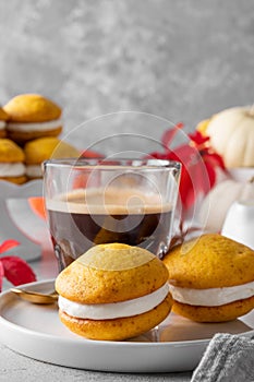 Pumpkin sandwich cookies with cream cheese on a gray concrete bsckground. Spicy autumn dessert. Copy space