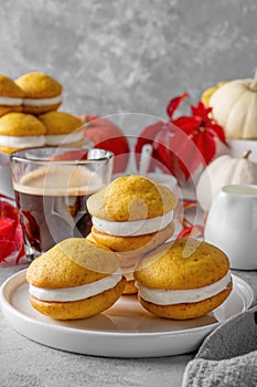 Pumpkin sandwich cookies with cream cheese on a gray concrete bsckground. Spicy autumn dessert. Copy space