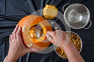 Pumpkin seed harvesting, womanâ€™s hand scooping seeds out of fresh pumpkin with a spoon