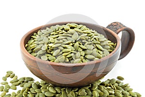 Pumpkin seeds in a clay bowl on a white background.