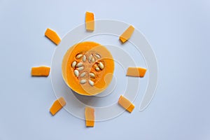 Pumpkin with seeds on a light background. Pieces are laid out in the shape of the sun.