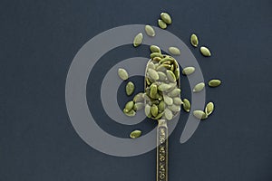 Pumpkin seeds in a wooden bowl and vintage scoop. Close up on a black background. copy space for text