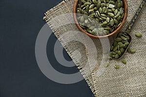 Pumpkin seeds in a wooden bowl and vintage scoop. Close up on a black background. copy space for text