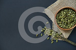 Pumpkin seeds in a wooden bowl and vintage scoop. Close up on a black background. copy space for text