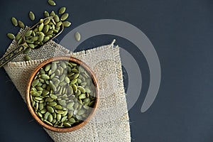 Pumpkin seeds in a wooden bowl and vintage scoop. Close up on a black background. copy space for text