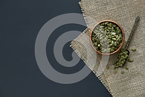 Pumpkin seeds in a wooden bowl and vintage scoop. Close up on a black background. copy space for text