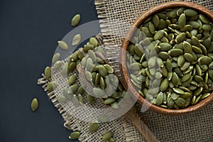 Pumpkin seeds in a wooden bowl and vintage scoop. Close up on a black background. copy space for text