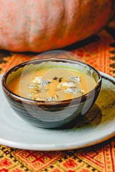 Pumpkin soup in a black bowl served on a rustic wooden Ukrainian table. Fall autumn menu concept