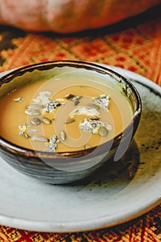 Pumpkin soup in a black bowl served on a rustic wooden Ukrainian table. Fall autumn menu concept