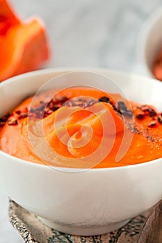 Pumpkin soup with black and chili flakes pepper, rye crispy toast on marble background.Traditional fall and winter dishes. Dietary